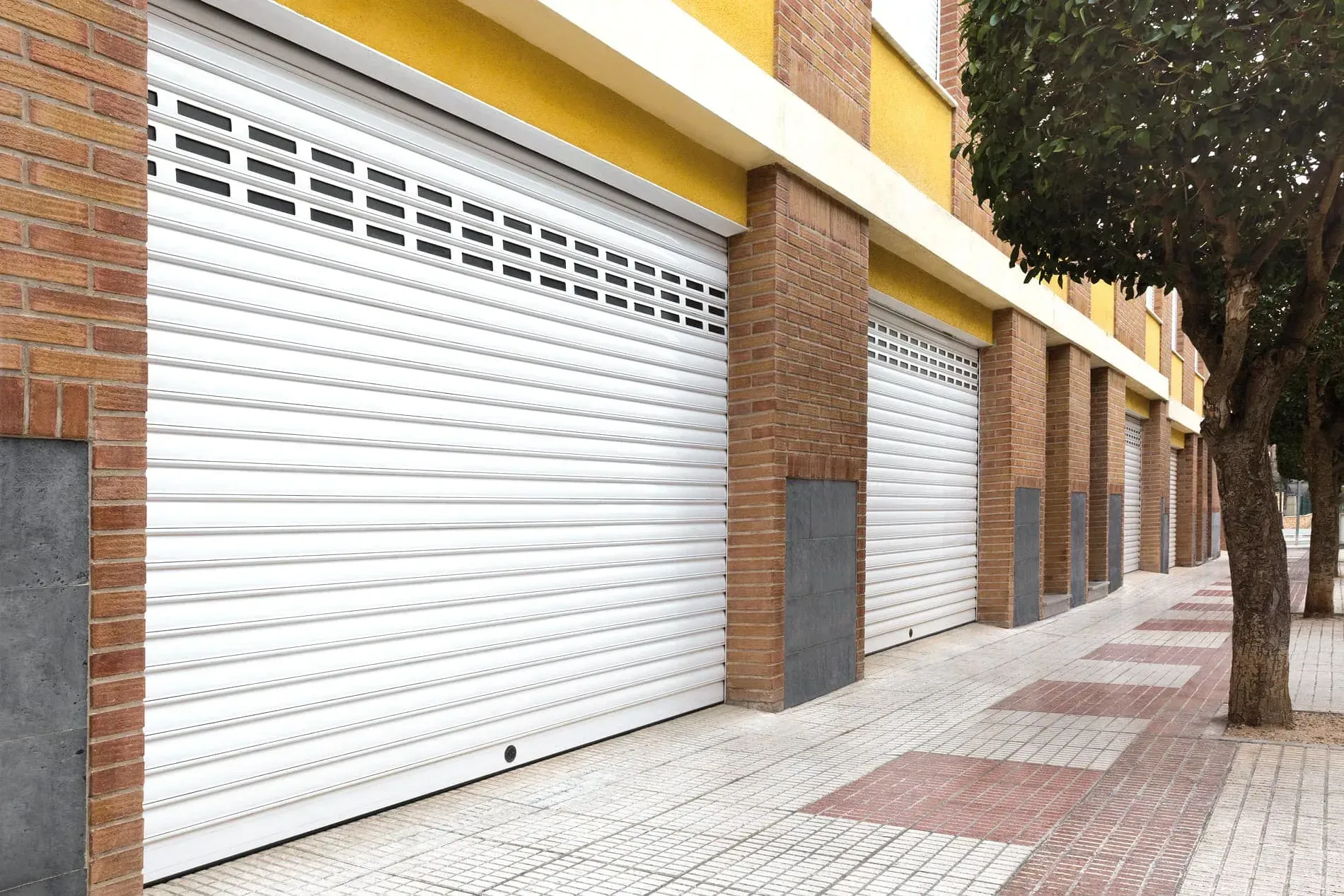 Una hilera de puertas de garaje blancas en un edificio de ladrillo.