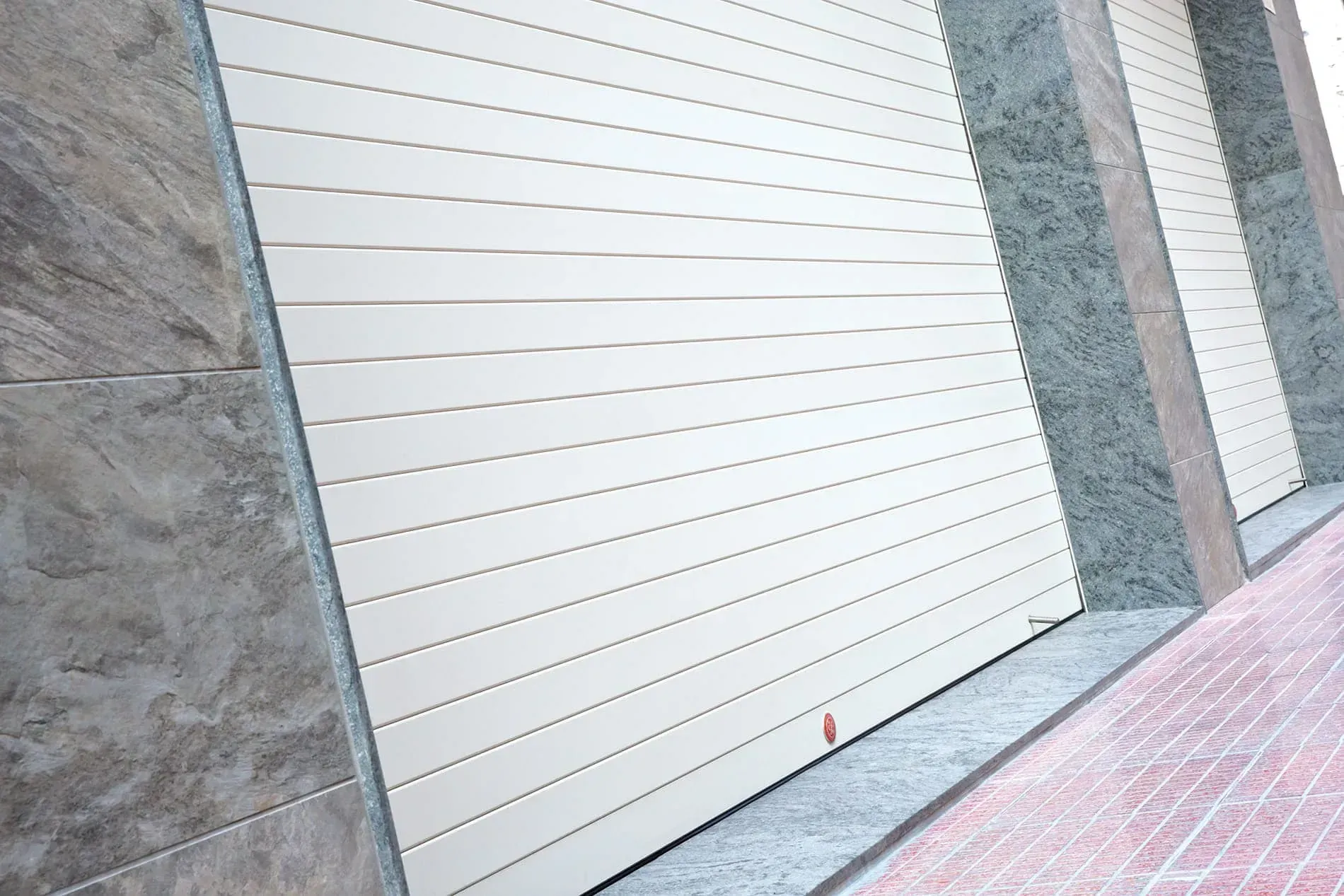 Una puerta de garaje blanca está situada al costado de un edificio.