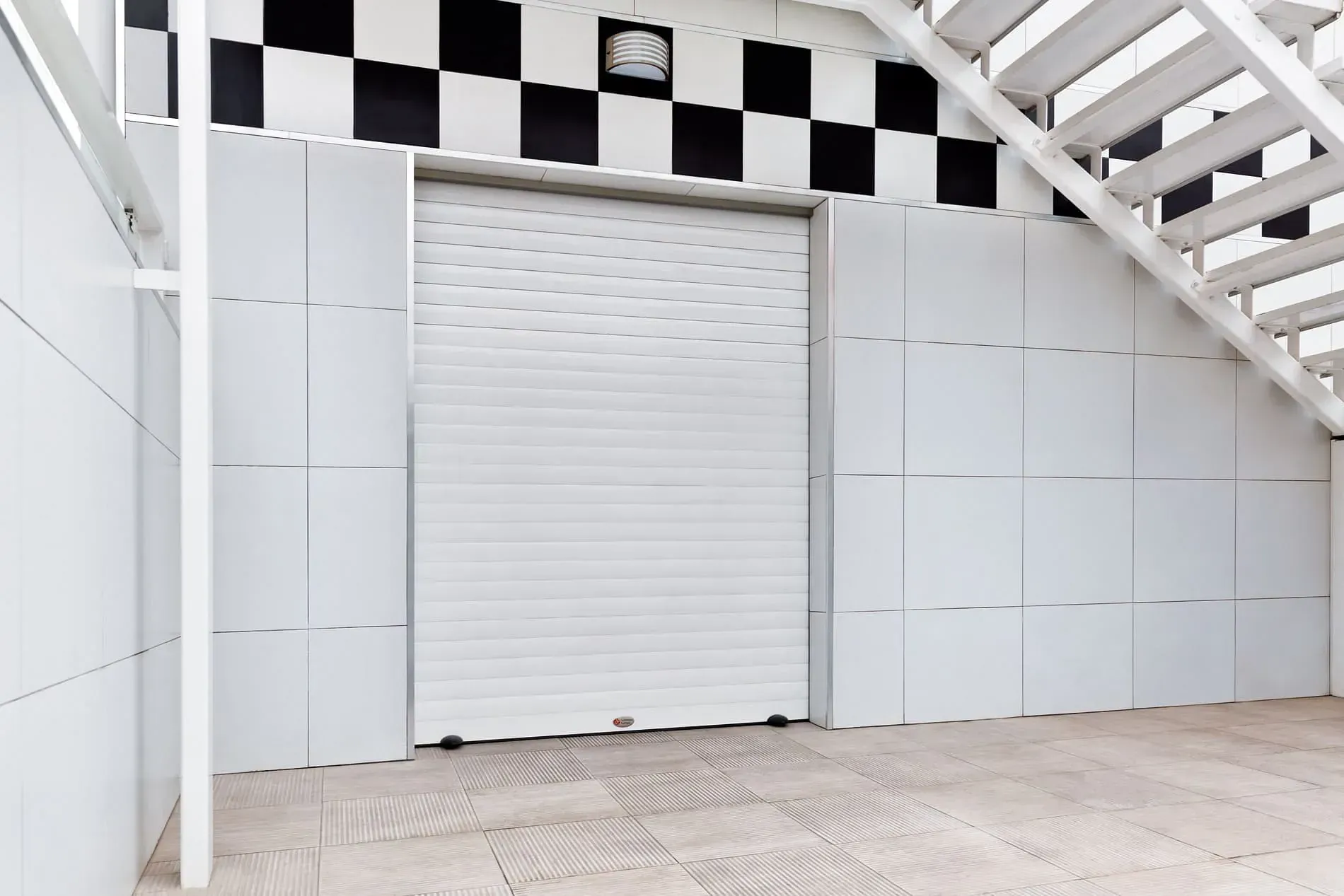 Una puerta de garaje blanca con una pared a cuadros en blanco y negro y escaleras.