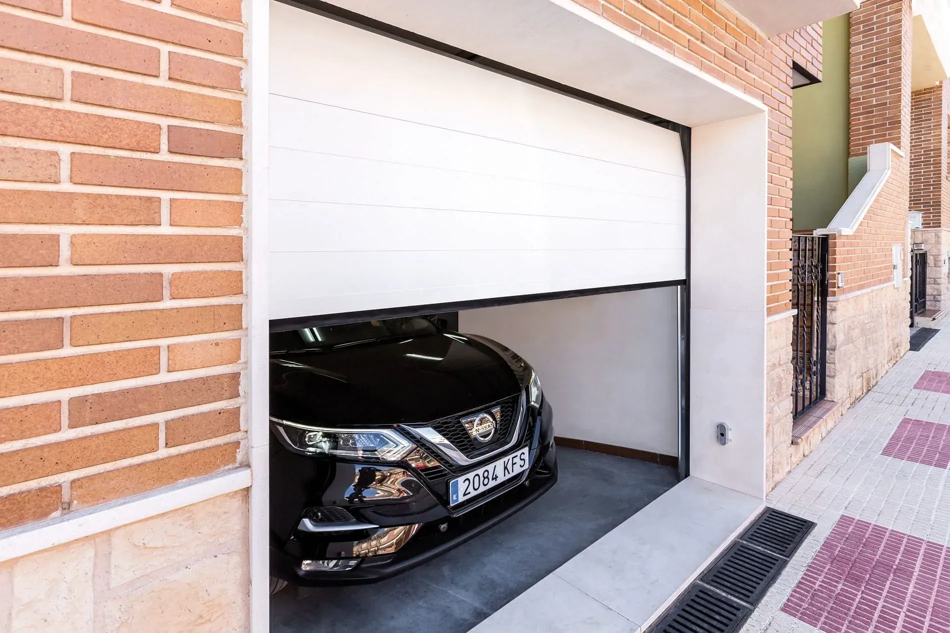 Un coche negro está aparcado en un garaje con la puerta abierta.