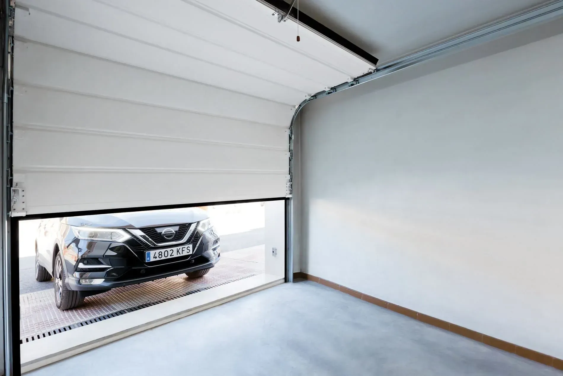 Un coche está aparcado en un garaje con la puerta abierta.