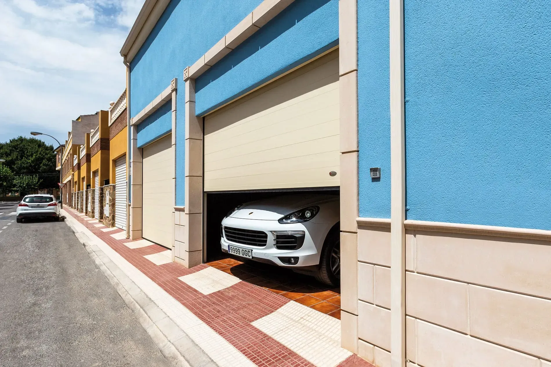 Un coche blanco está aparcado en un garaje con la puerta abierta.