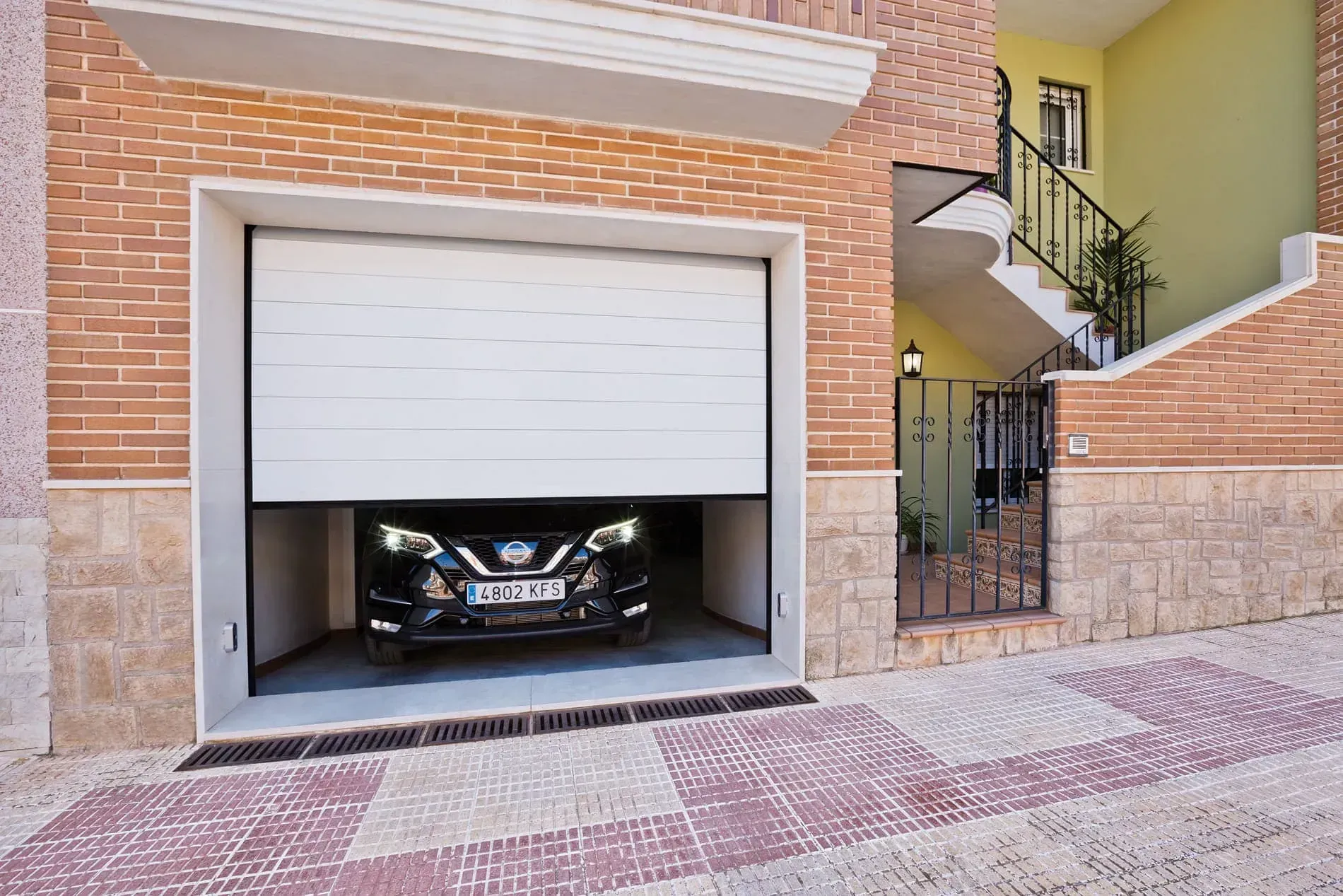 Un coche está aparcado en un garaje con la puerta abierta.