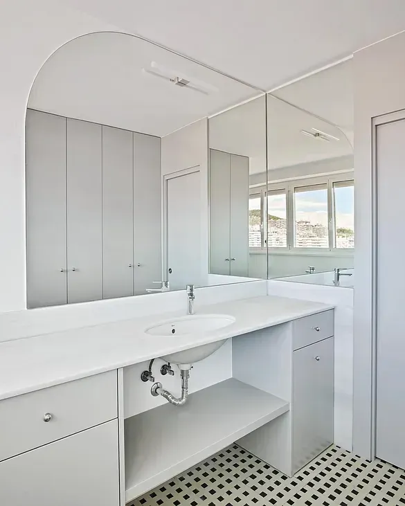 Un baño con lavabo, espejo y armarios.