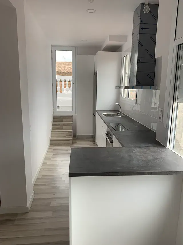 Una cocina con gabinetes blancos y una encimera negra.