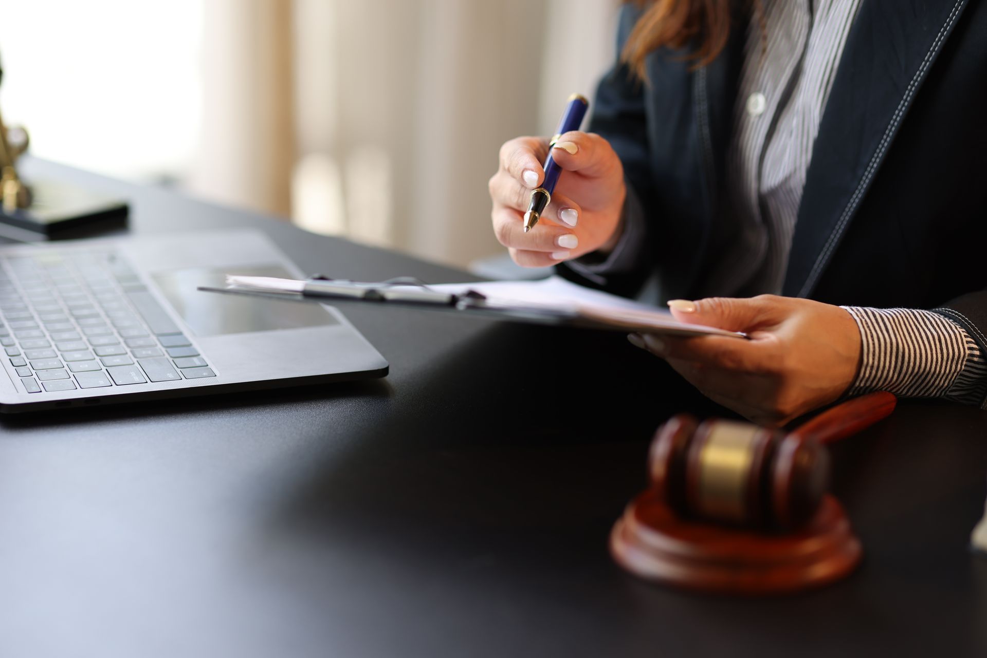 Une personne examine des documents à un bureau avec un ordinateur portable et un marteau à proximité