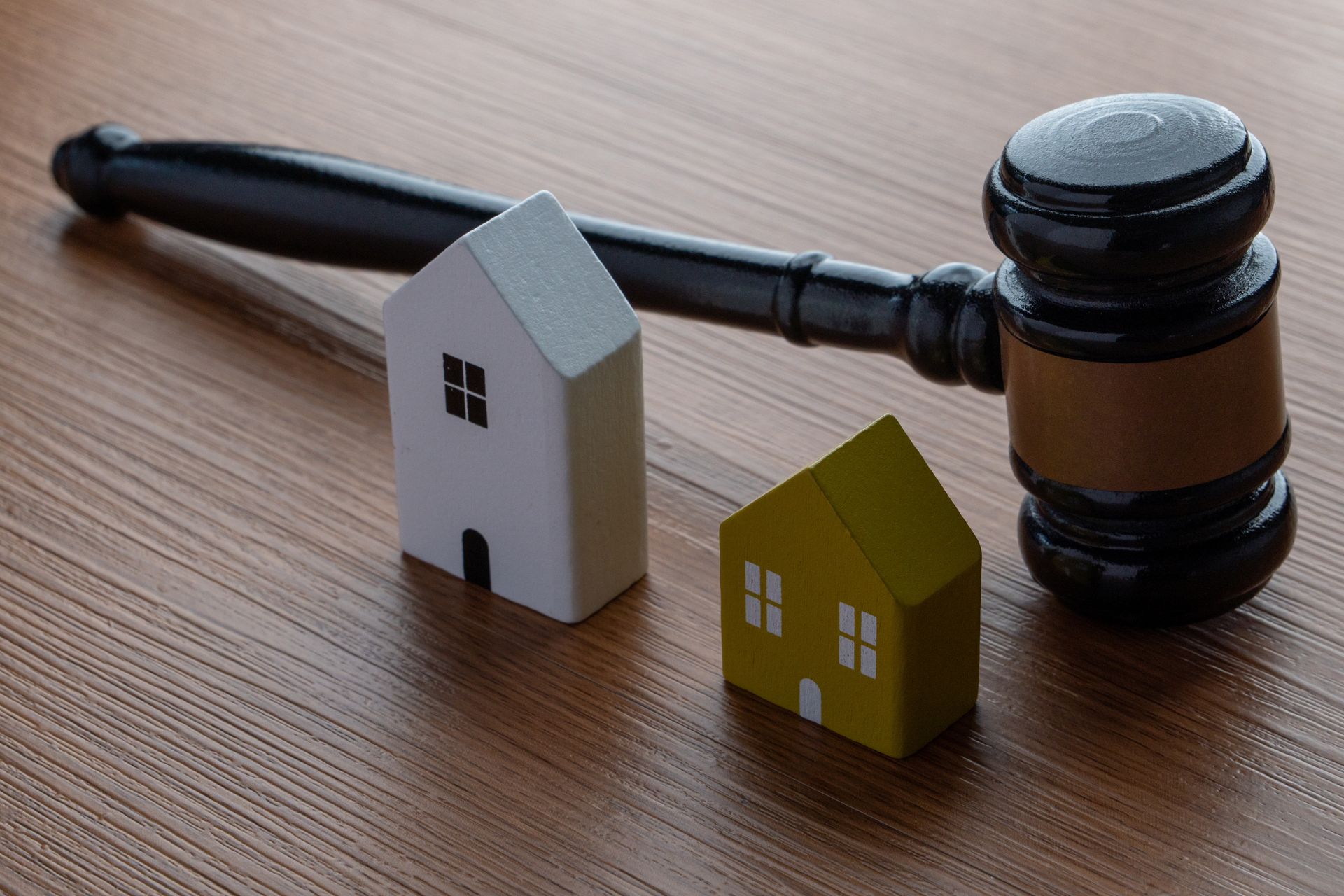 Le marteau du juge à côté de deux petites maquettes de maisons sur une table en bois