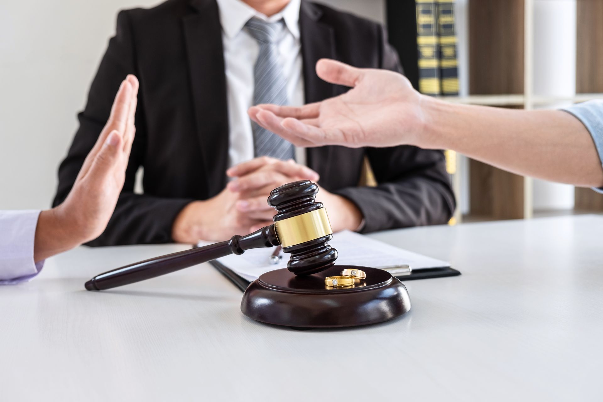 Des mains se tendent vers un maillet posé sur une table lors d'une réunion d'affaires