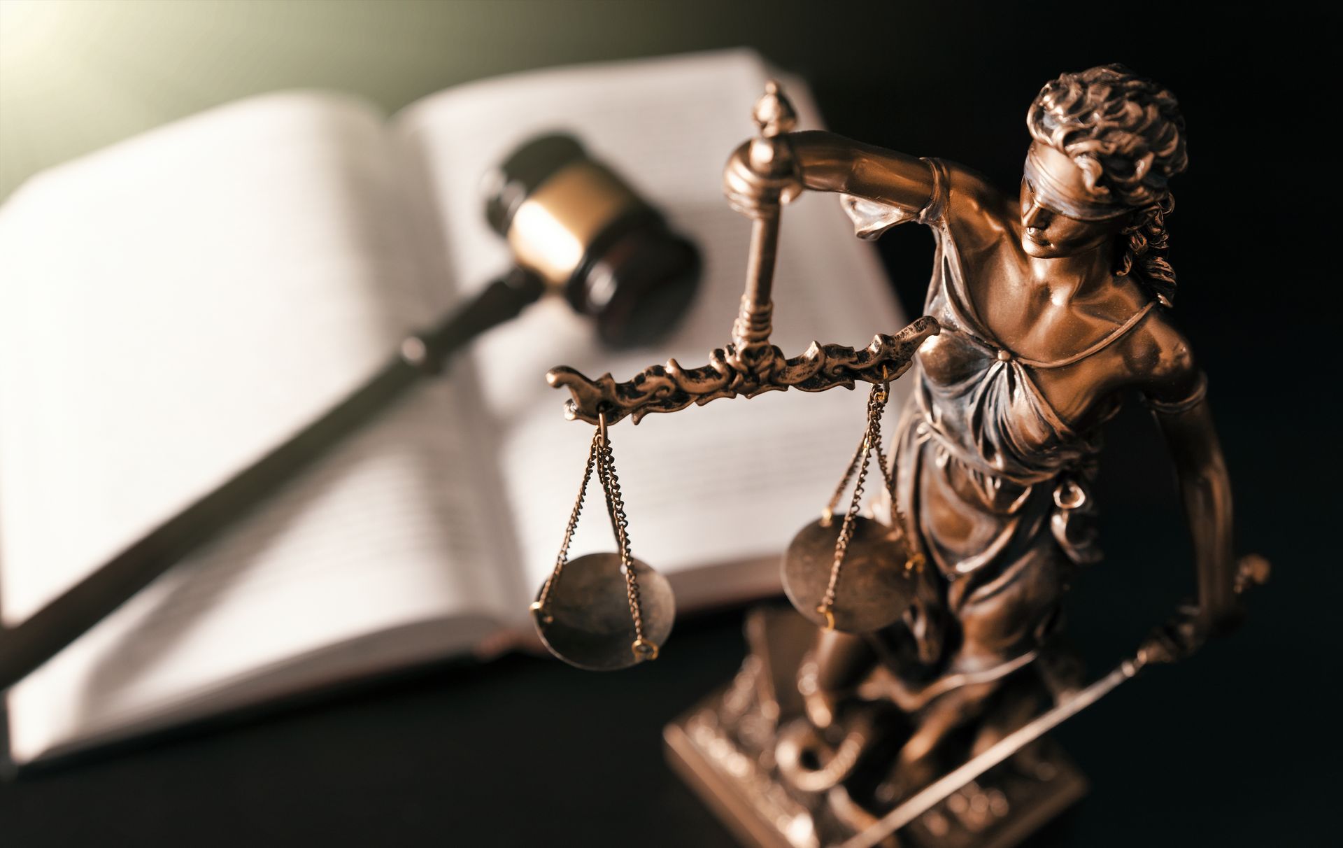 Statue en bronze de la dame de la justice, tenant une balance, un maillet et un livre ouvert.