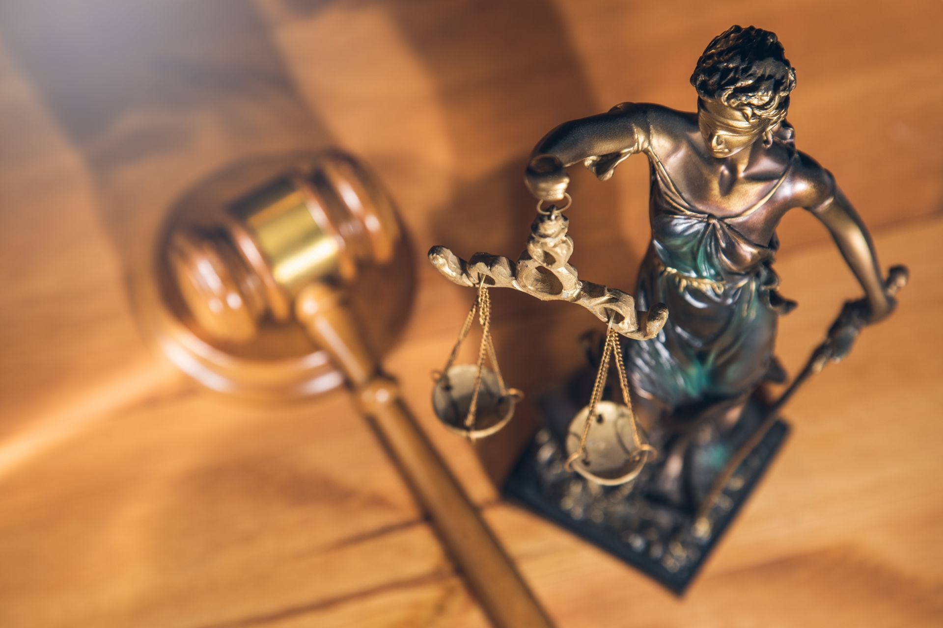 Statue de la justice à côté d'un maillet sur un bureau en bois, symbolisant la loi et la justice