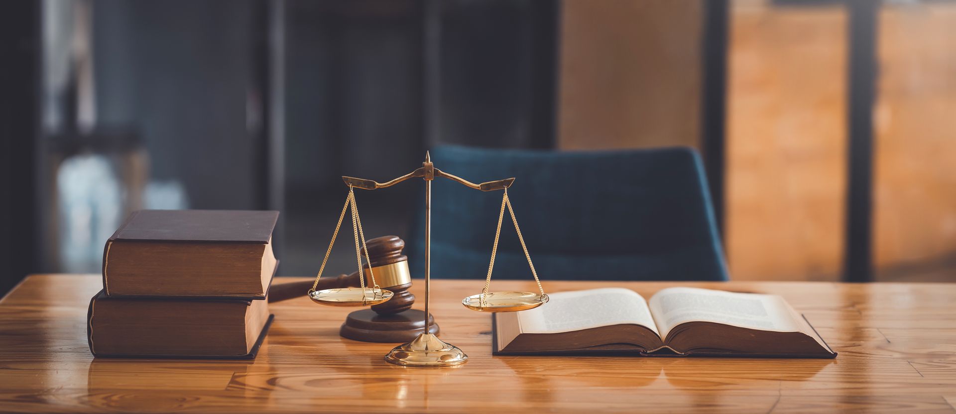 Bureau d'avocat avec des livres empilés, une balance de la justice et un livre ouvert sur une table en bois, baignant dans une lumière chaleureuse