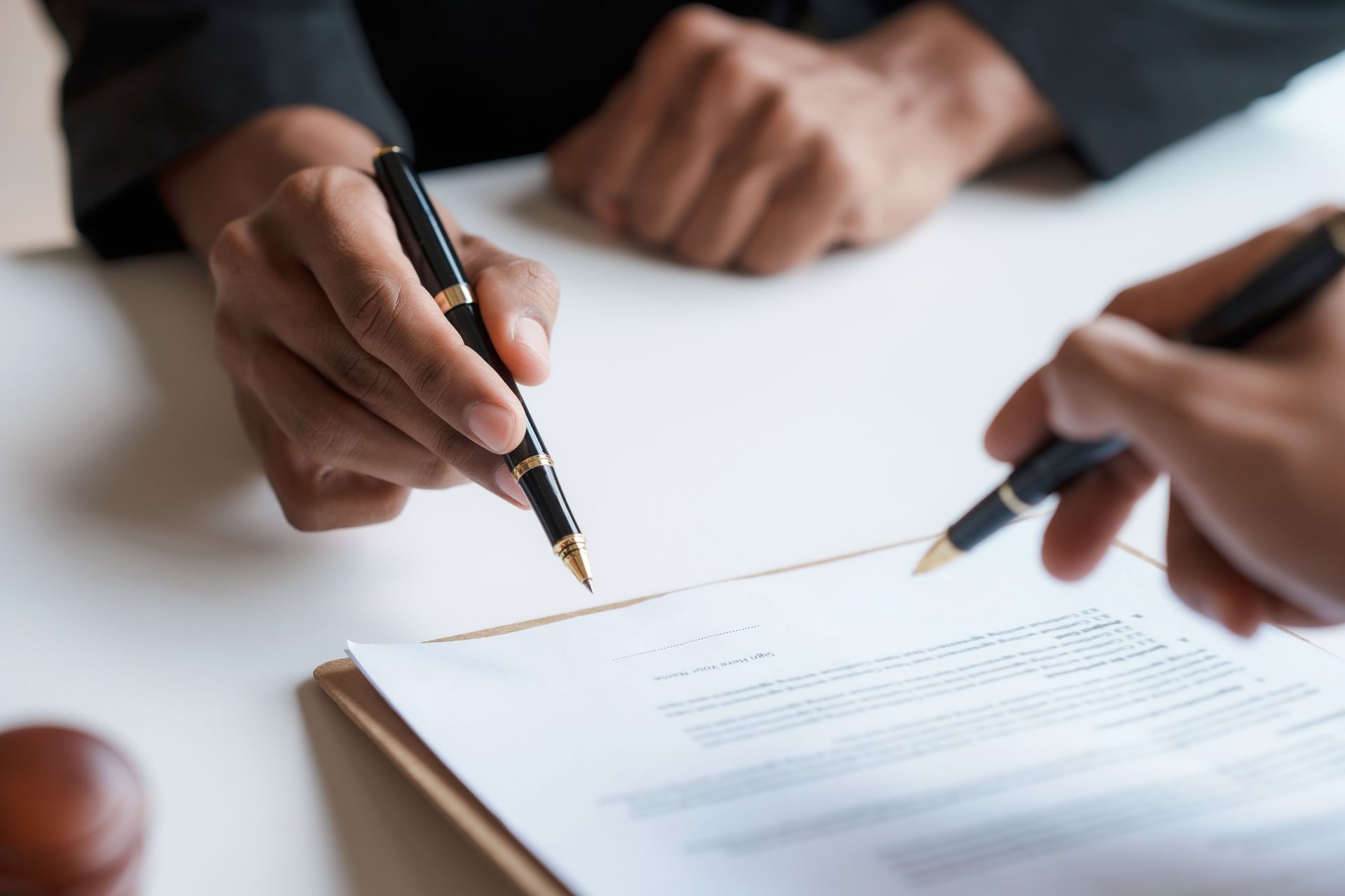 Deux personnes signent un document avec des stylos à un bureau