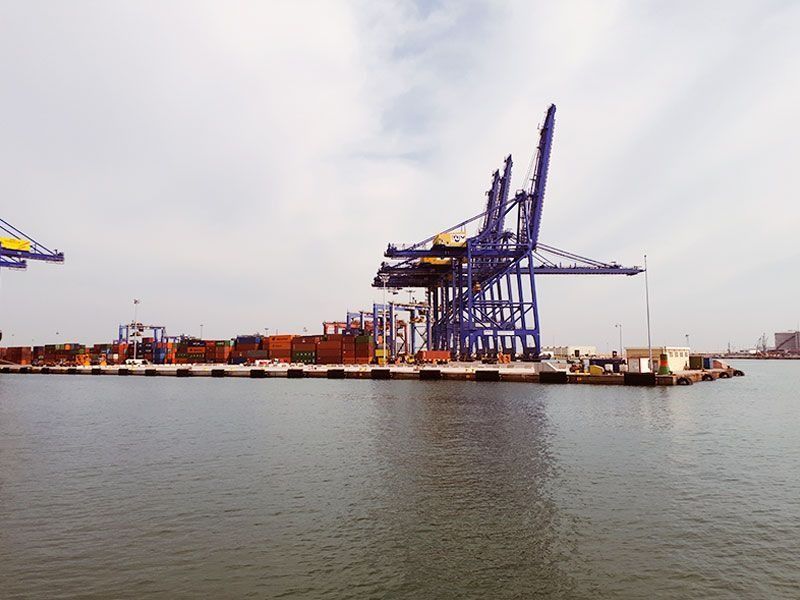 Una gran grúa azul está sentada sobre un gran cuerpo de agua.