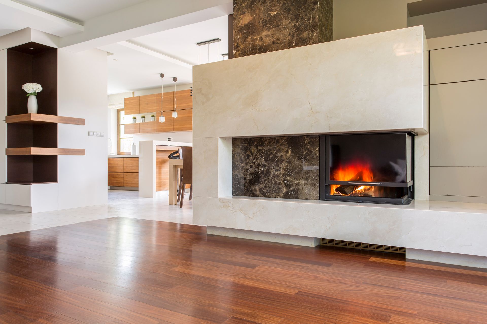 Salon moderne avec parquet, cheminée blanche et foyer crépitant.
