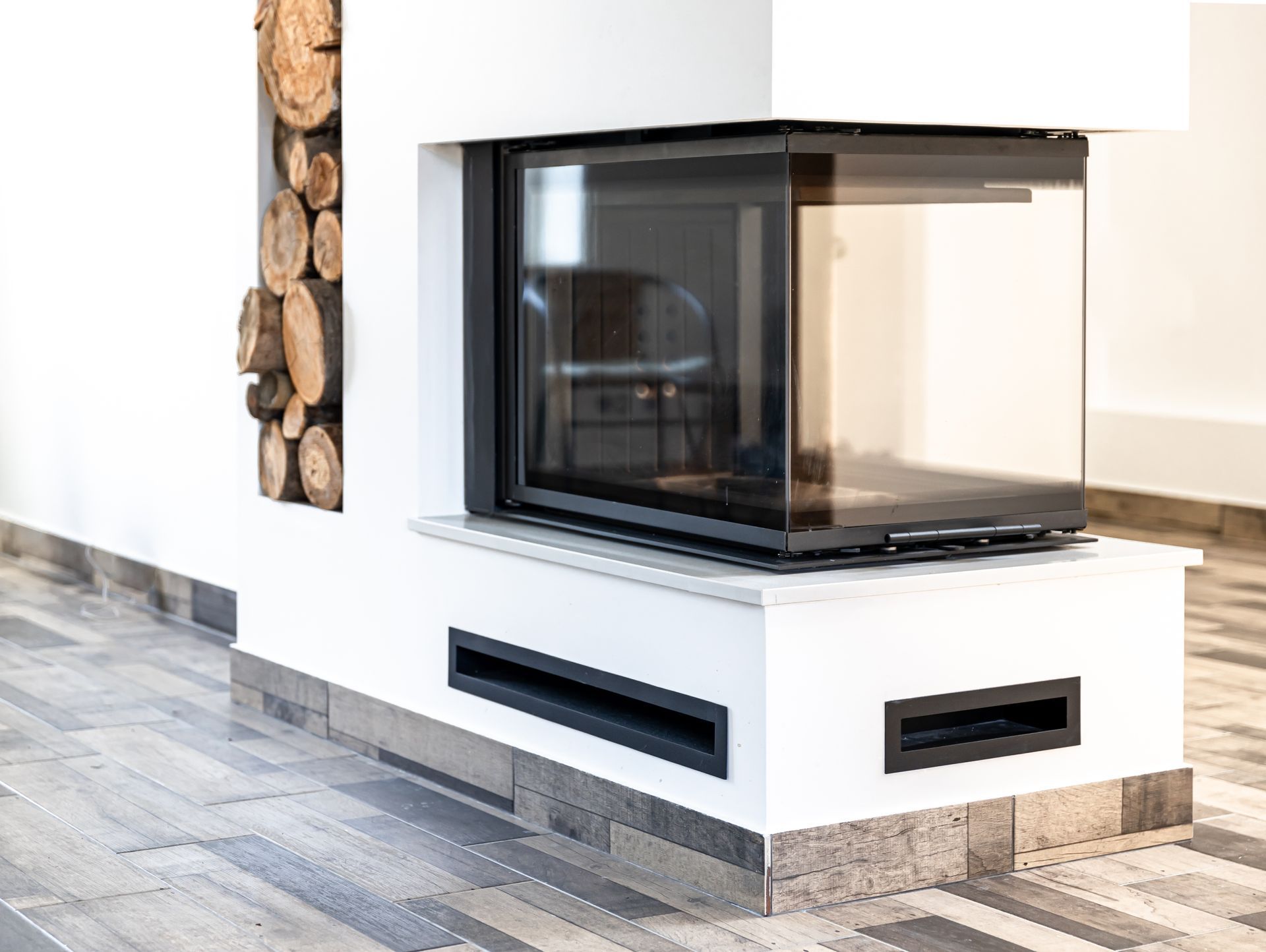 Cheminée blanche moderne avec foyer en verre noir dans un salon minimaliste et lumineux