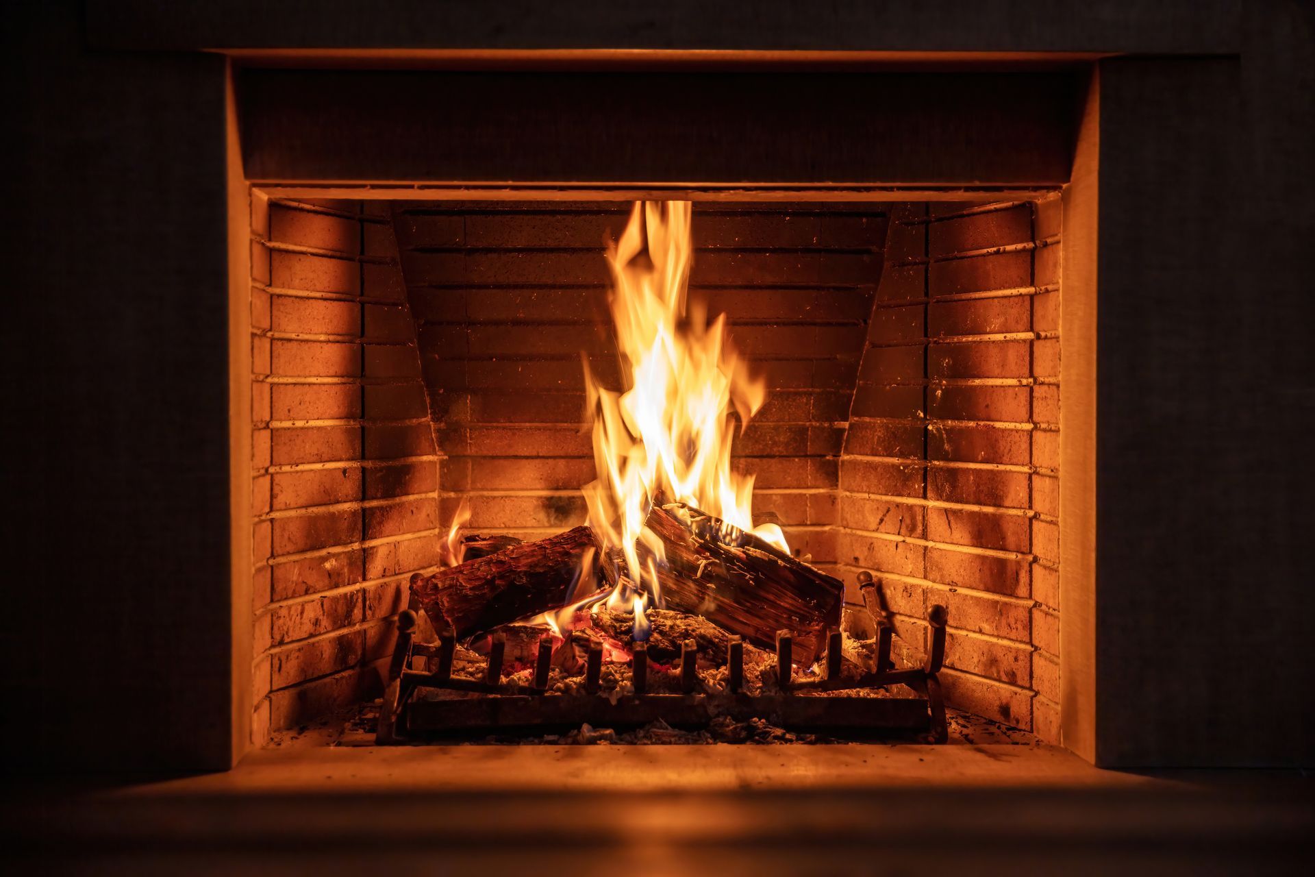 Cheminée allumée avec des flammes vives et des bûches incandescentes à l'intérieur d'un foyer en briques