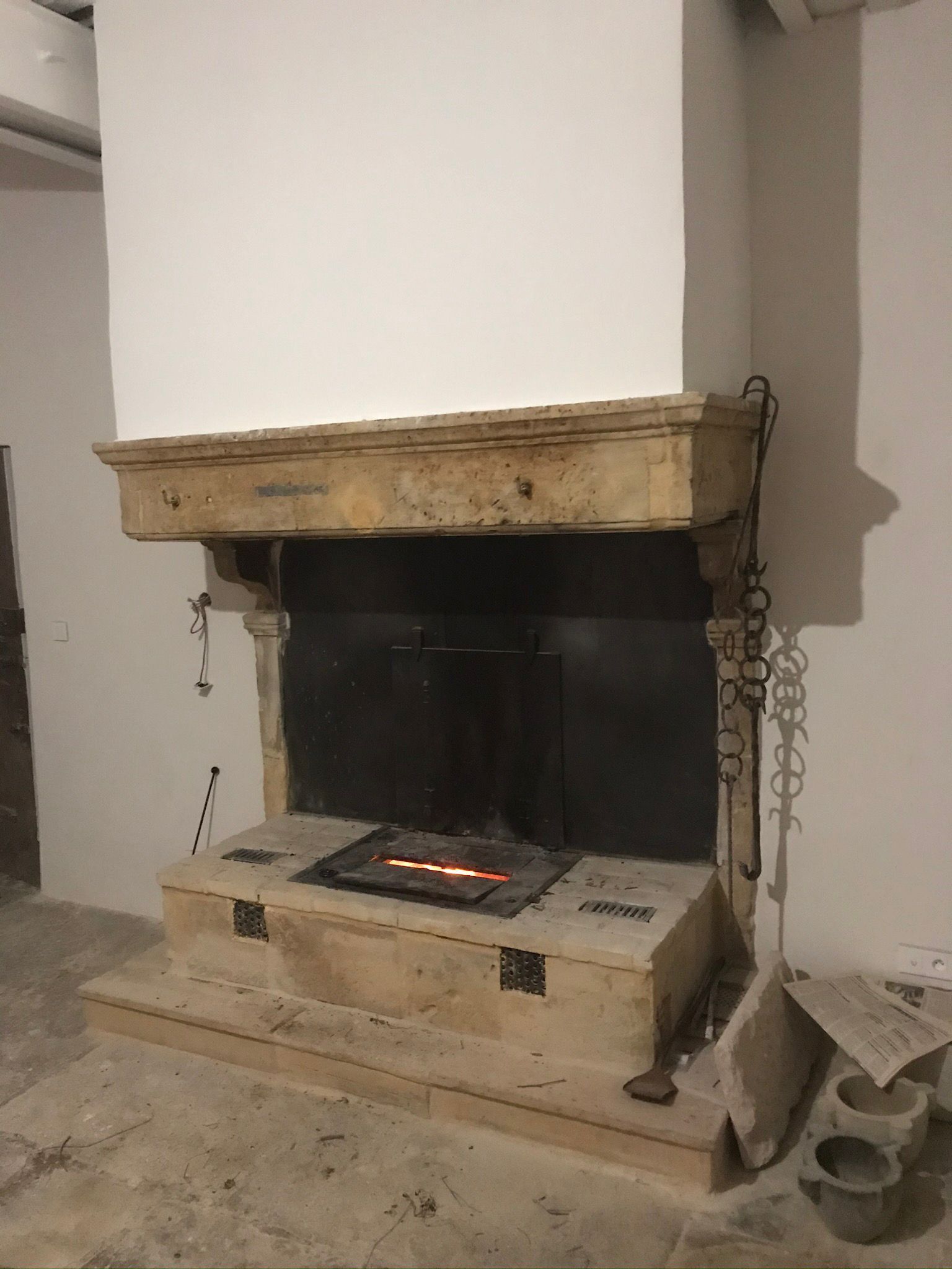 Vieille cheminée en pierre avec un petit feu qui brûle à l'intérieur dans une pièce rustique.