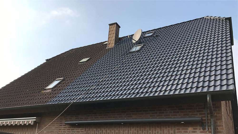 Das Dach eines Hauses mit einem Schornstein und einer Satellitenschüssel darauf.