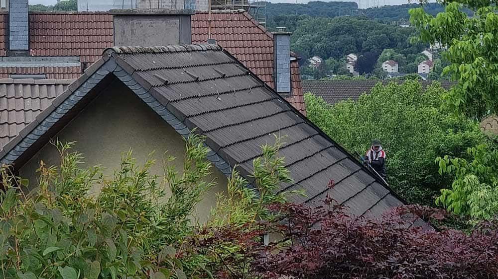 Ein Haus mit einem Dach, das von Bäumen und Büschen umgeben ist.