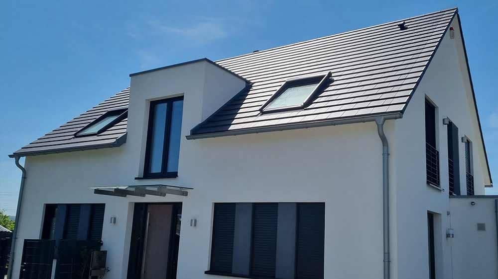 Ein weißes Haus mit einem Dach, auf dem sich ein Oberlicht befindet.