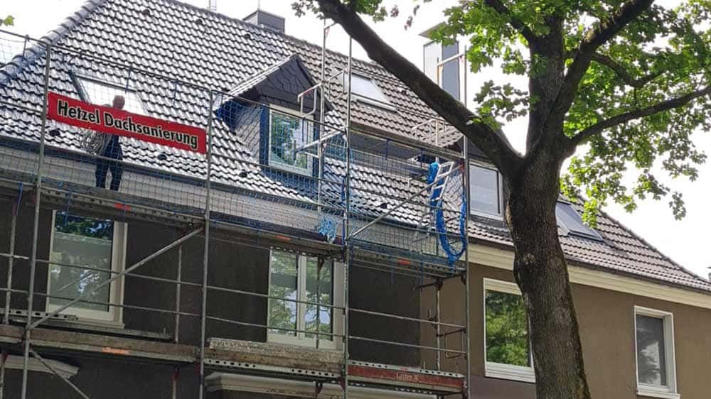 Ein Mann steht auf einem Gerüst an der Seite eines Gebäudes.