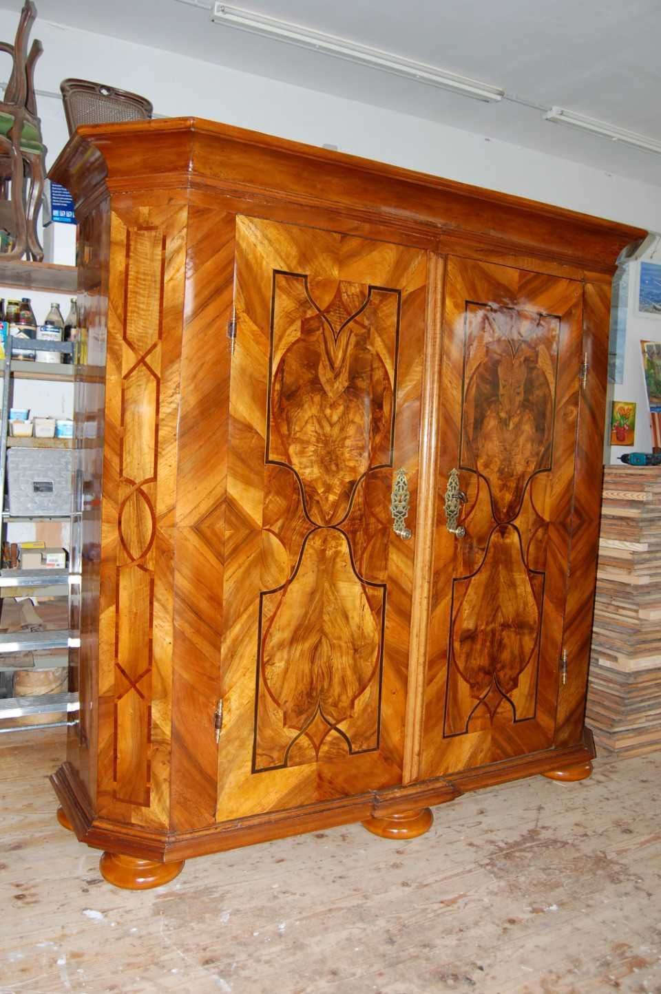 Verschnörkelter Holzschrank mit geschnitzten Türen und glänzender Oberfläche in einer Werkstatt oder einem Lagerraum