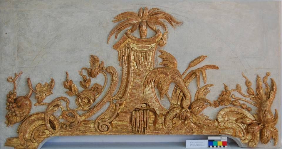 Ornate goldene Zierornamente mit Palmblättern und floralen Ranken auf einer hellen Wand