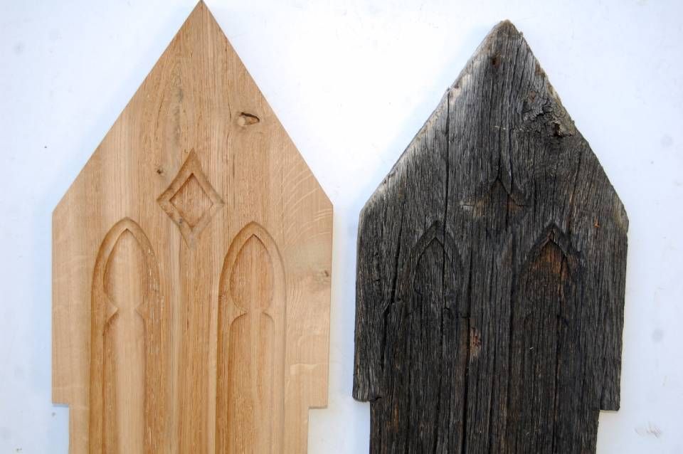 Zwei kleine hausförmige Holzstücke, eines aus hellem Holz und eines aus dunkel gebeiztem Holz, nebeneinander.