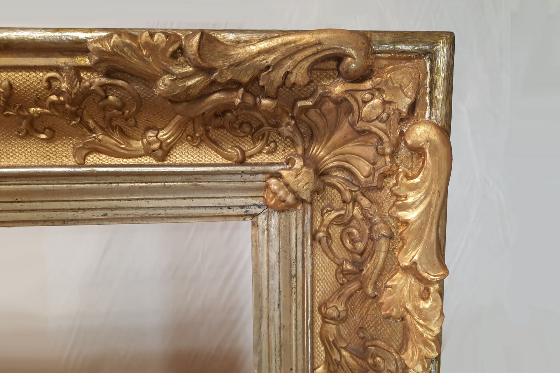 Nahaufnahme einer kunstvollen Ecke eines goldenen Bilderrahmens mit geschnitzten floralen Details