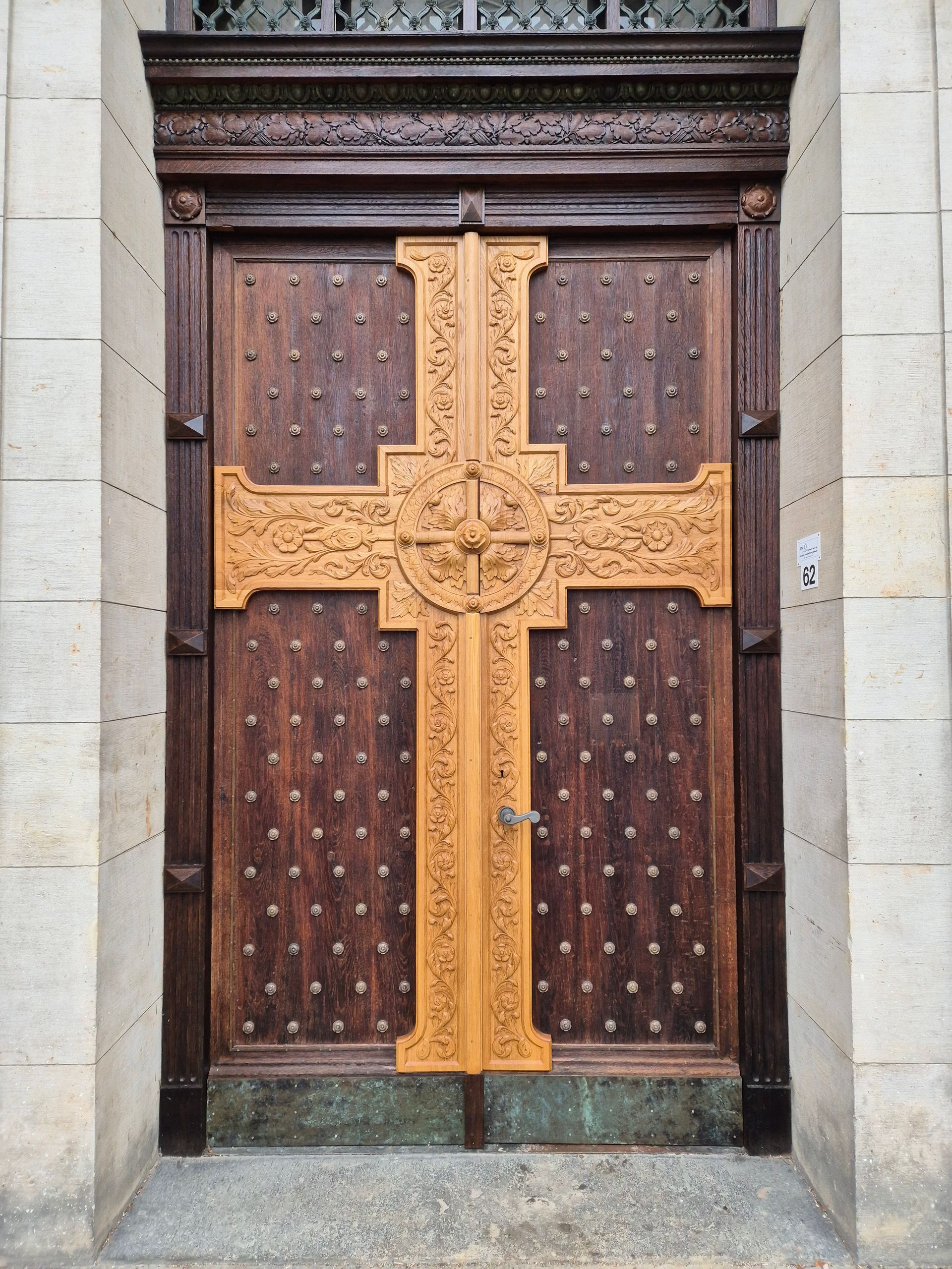 Holzkirchentür mit einem großen goldenen Kreuz und kunstvollen Schnitzereien