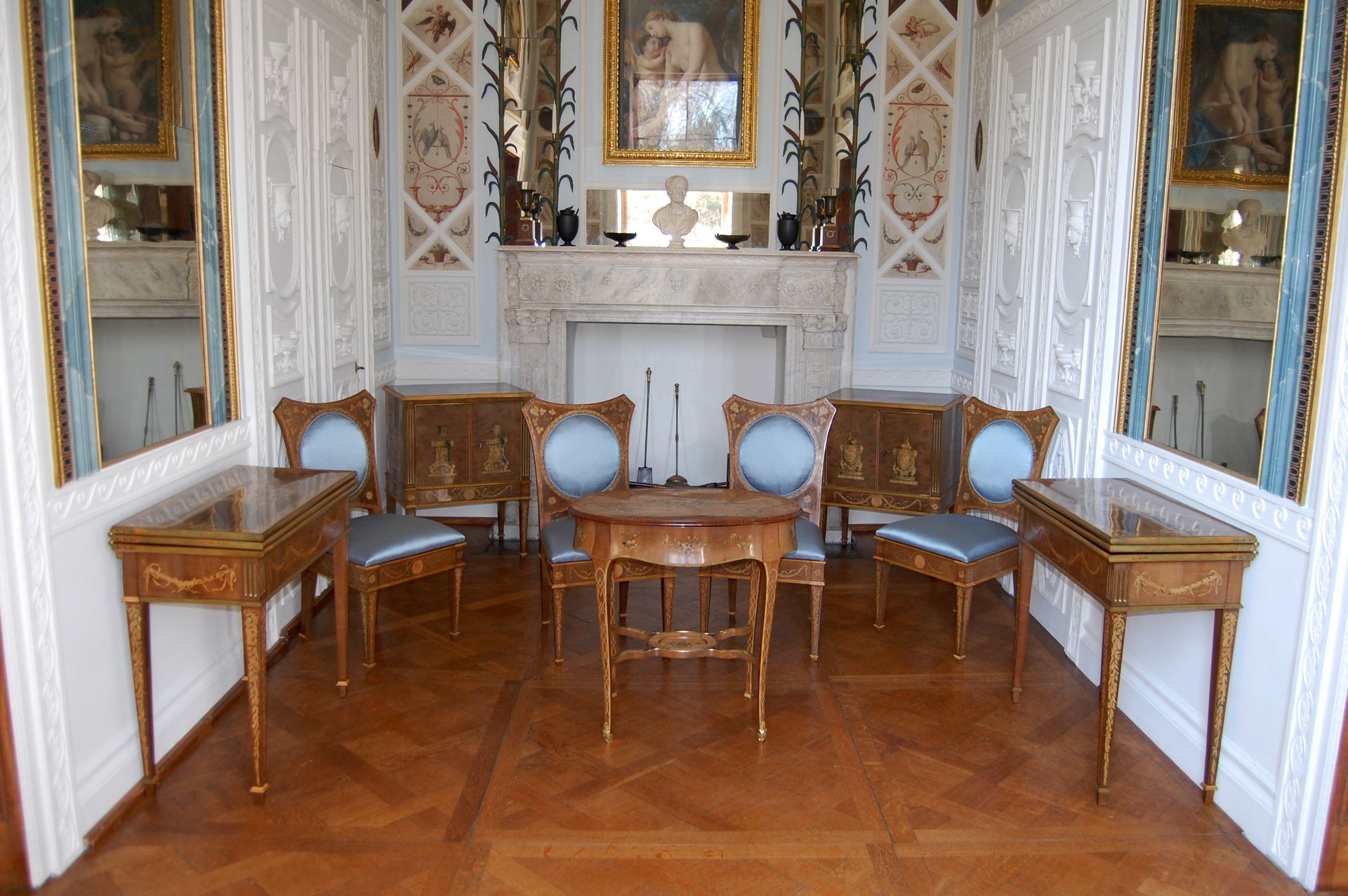 Elegantes Wohnzimmer mit vier Korbsesseln, einem kleinen Tisch und verspiegelten Wänden auf einem Parkettboden