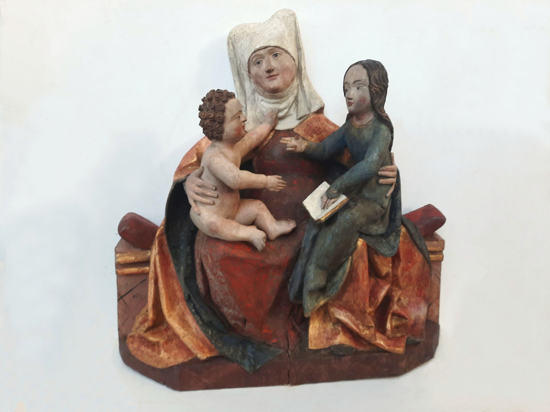 Kleine bemalte Skulptur einer sitzenden Frau, die ein Kind hält, mit einem weiteren Kind an ihrer Seite.