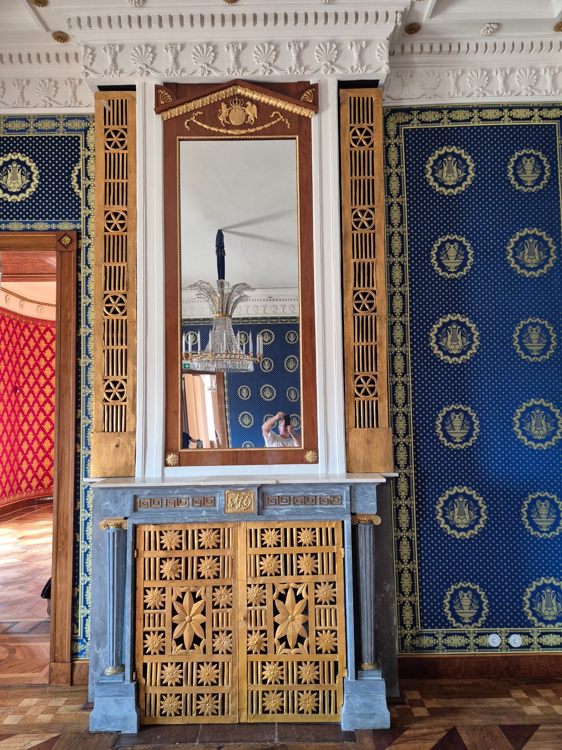 Aufwendig gestaltete blau-goldene Innenwand mit Spiegel, geschnitzter Holzvertäfelung und dekorativem Türrahmen