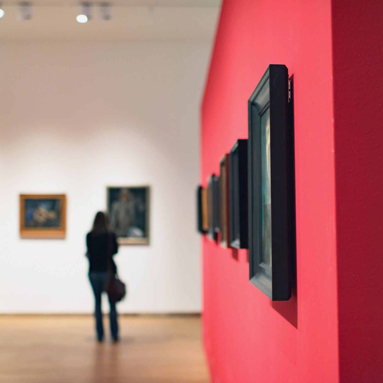 a red wall with a row of framed pictures on it