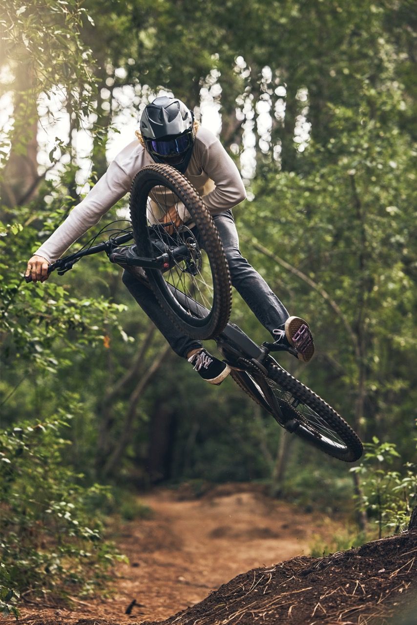 a man is doing a trick on a mountain bike in the woods .