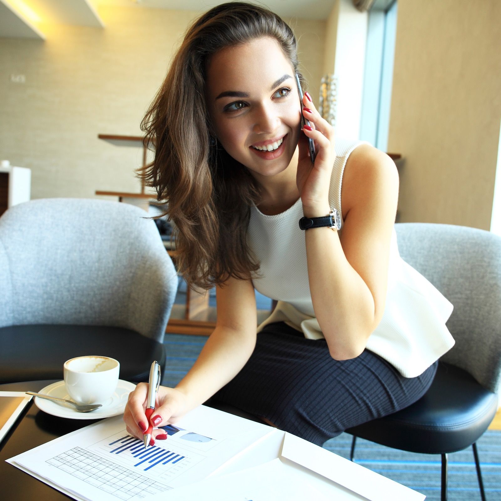 a woman is sitting at a table talking on a cell phone