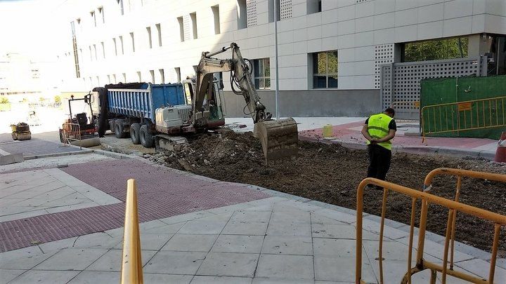 Un hombre con un chaleco amarillo está parado frente a un sitio de construcción.