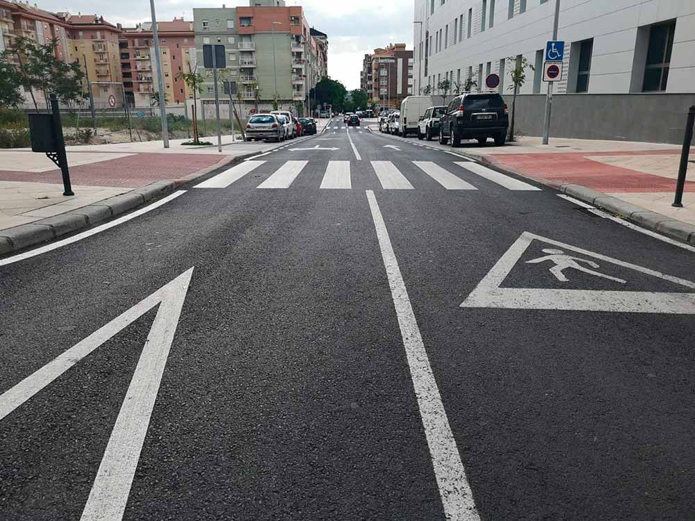 Una calle con un paso de peatones y una señal para discapacitados.