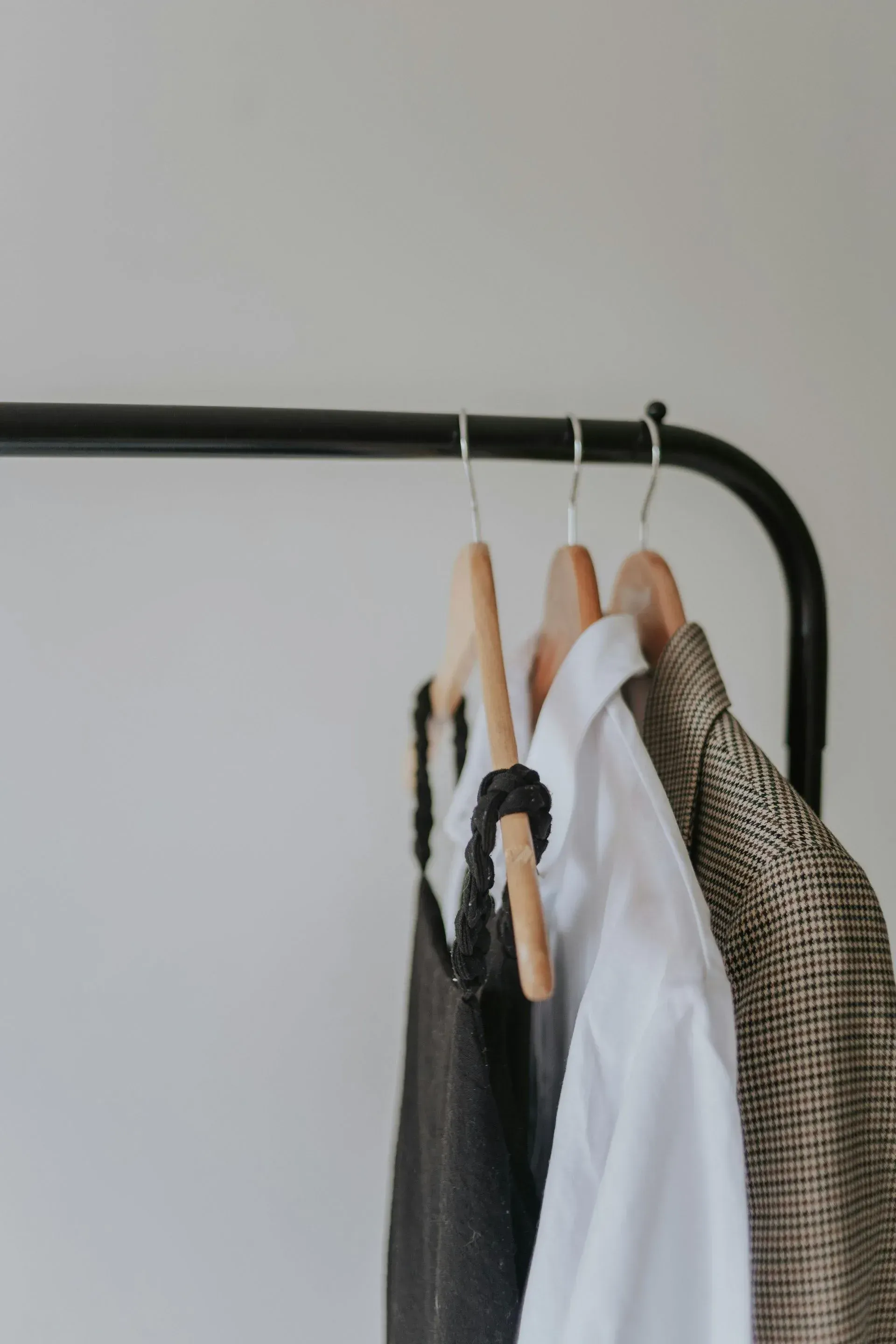 Tres prendas —un vestido negro, una camisa blanca y un blazer marrón estampado.