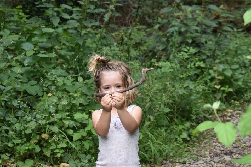 Älteres Mädchen füttert Baby drinnen mit Löffel.