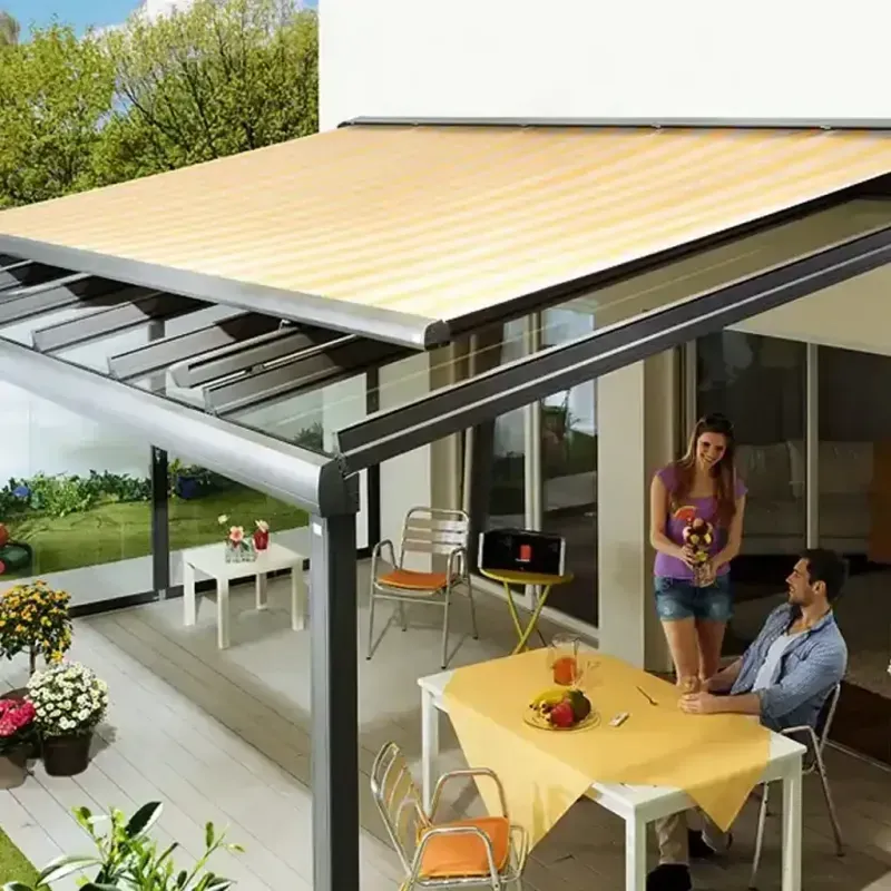 Paar auf der Terrasse unter einer beigen Markise, genießt Essen an einem Tisch.