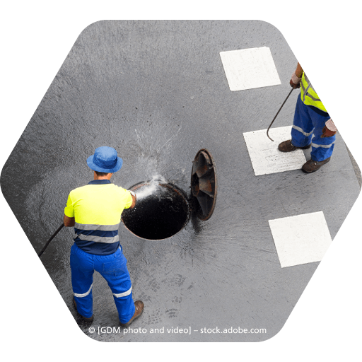 Zwei Männer arbeiten an einem Kanaldeckel auf der Straße, Rohrreinigung Frank Welbers