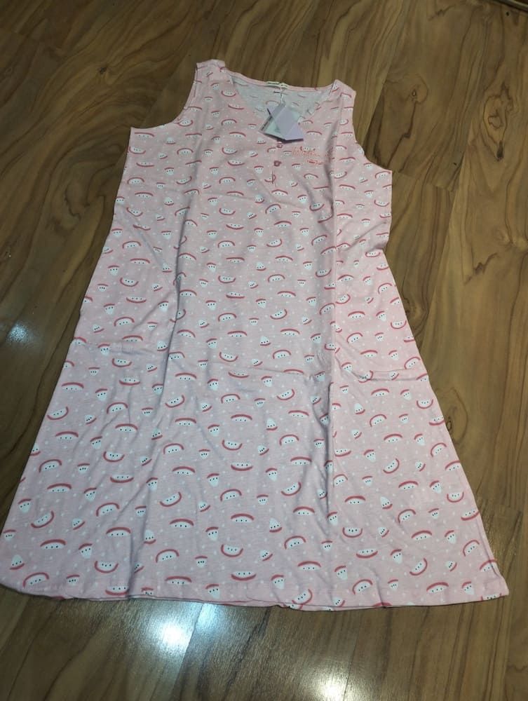 Un camisón rosa claro, sin mangas y hasta la rodilla, con un estampado repetitivo de pequeños arcoíris rojos y blancos.