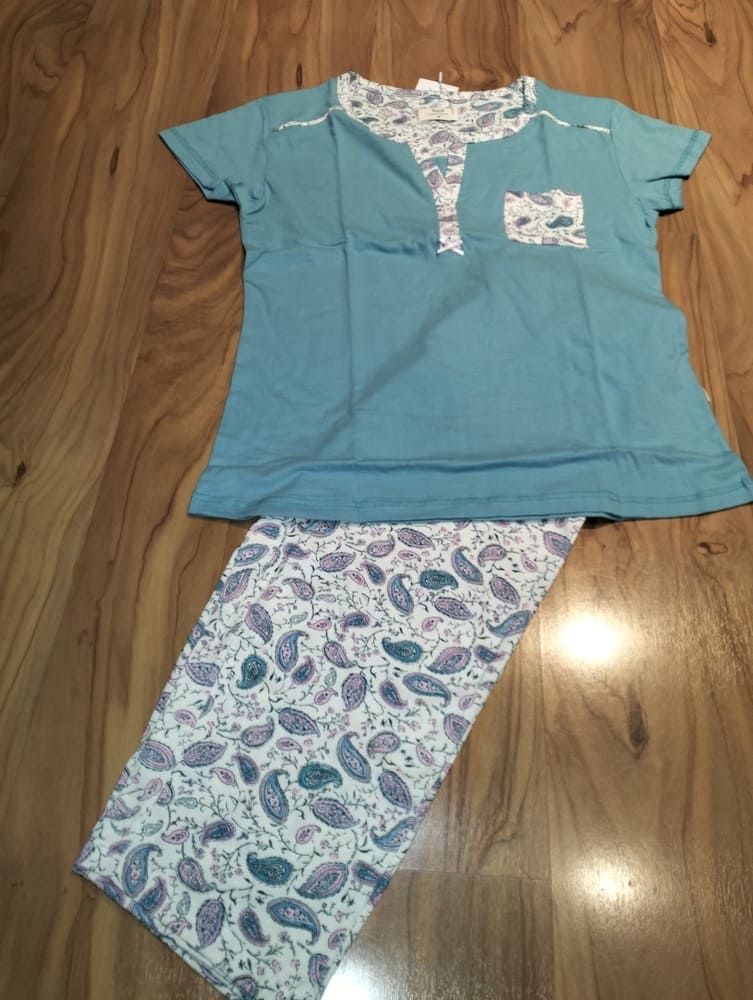 Una blusa de manga corta color verde azulado con bolsillo y escote con estampado de cachemir, combinada con pantalones a juego con el mismo estampado.