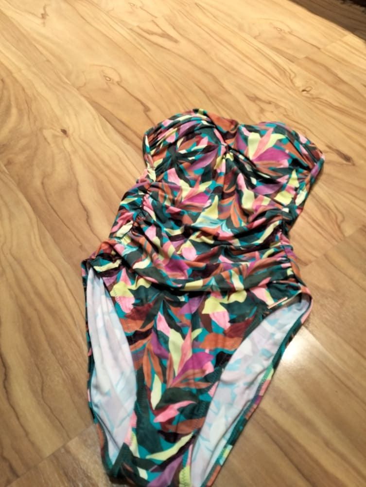 Un bañador de una sola pieza sin tirantes con un colorido estampado floral abstracto en tonos verdes, amarillos y morados.