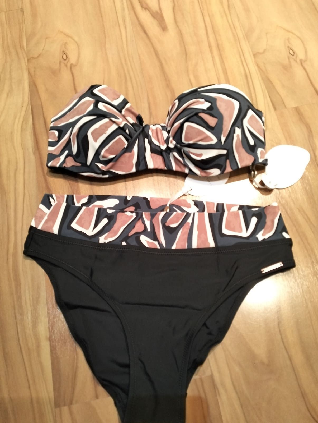Un bikini de dos piezas que incluye un top sin tirantes con estampado de formas en color tostado y negro, y una braguita negra lisa de talle alto.