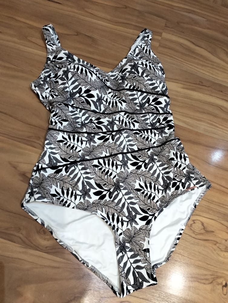 Un bañador de una pieza con estampado botánico de hojas en negro, blanco y beige, y detalles fruncidos horizontales.