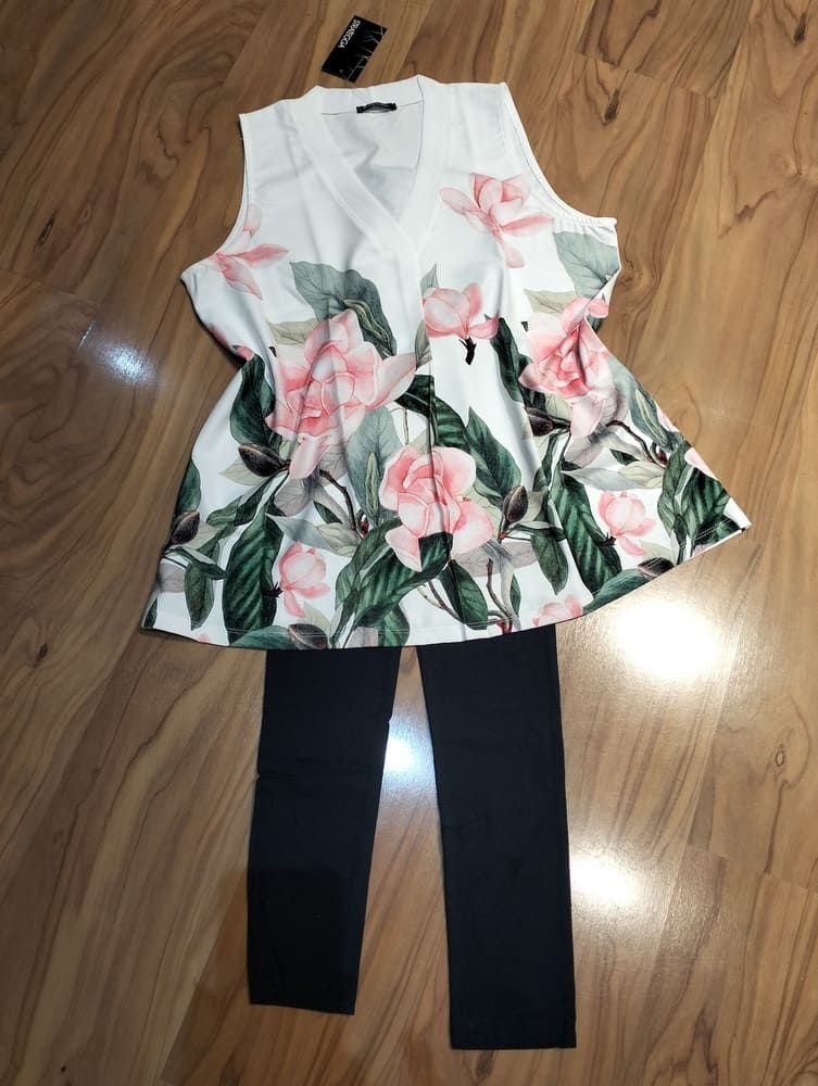 Un vestido de verano blanco, sin mangas, de largo midi, con ribete de encaje y detalles escalonados, extendido sobre un suelo de madera clara.