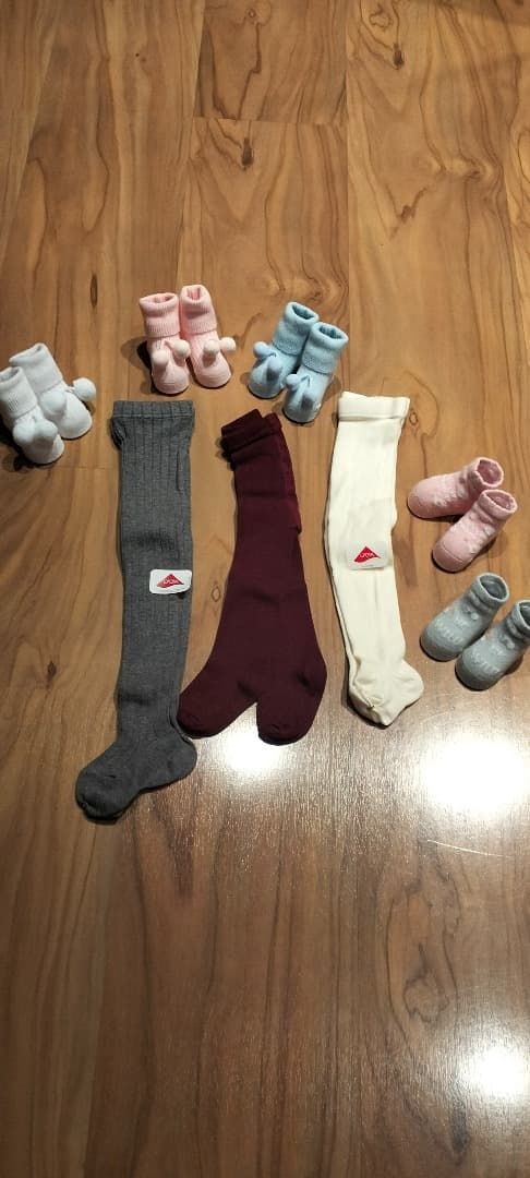Cuatro pares de calcetines estampados colocados sobre un suelo de madera, cada uno con un pequeño animal de peluche a juego.