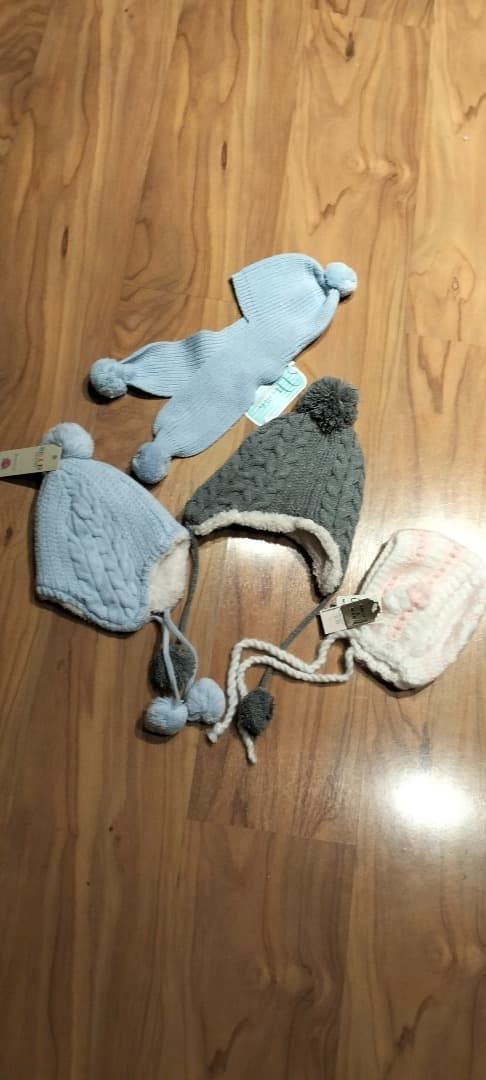 Tres animales de punto sobre un suelo de madera: un gato gris, un pájaro azul y un animal blanco enredados en un cordón